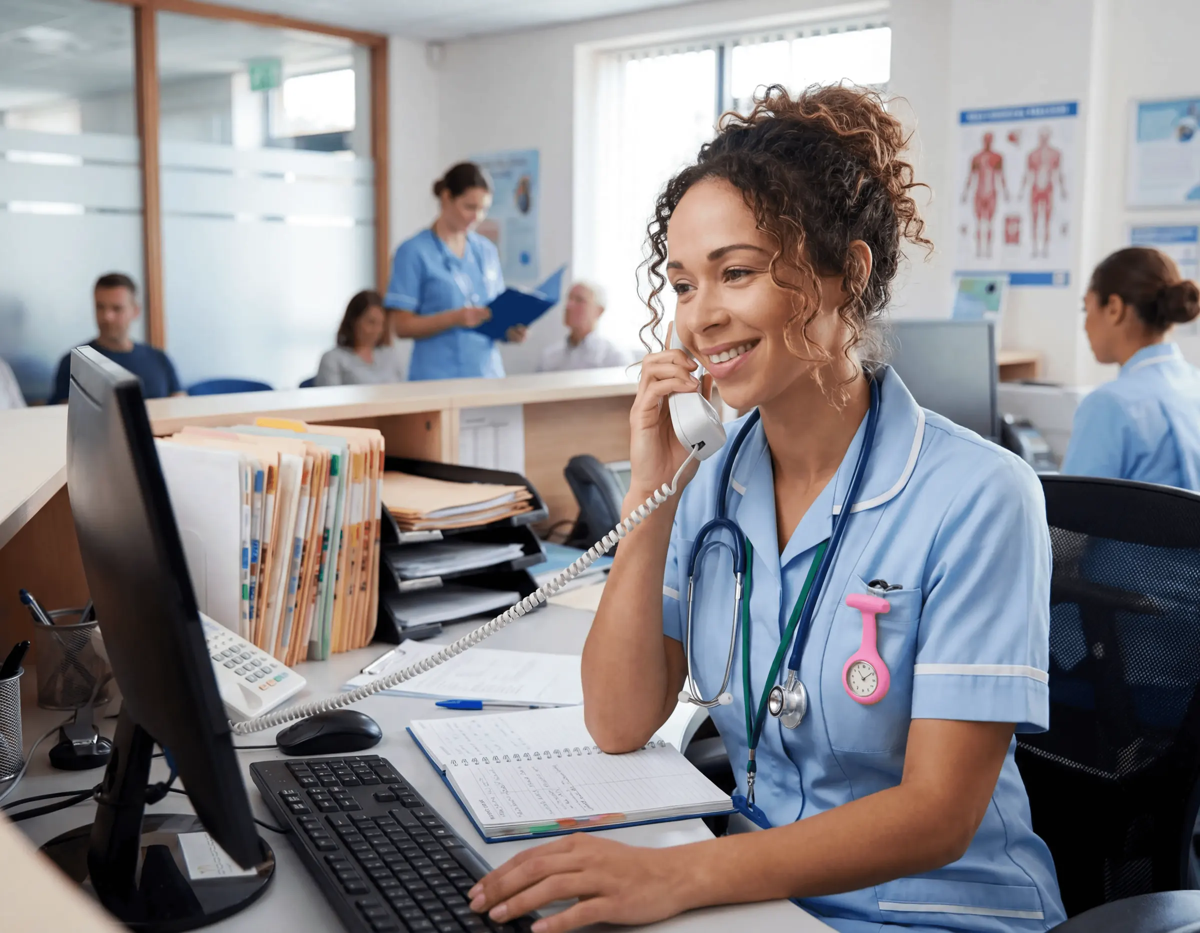 Receptionist in scrubs on the phone at a busy clinic front desk